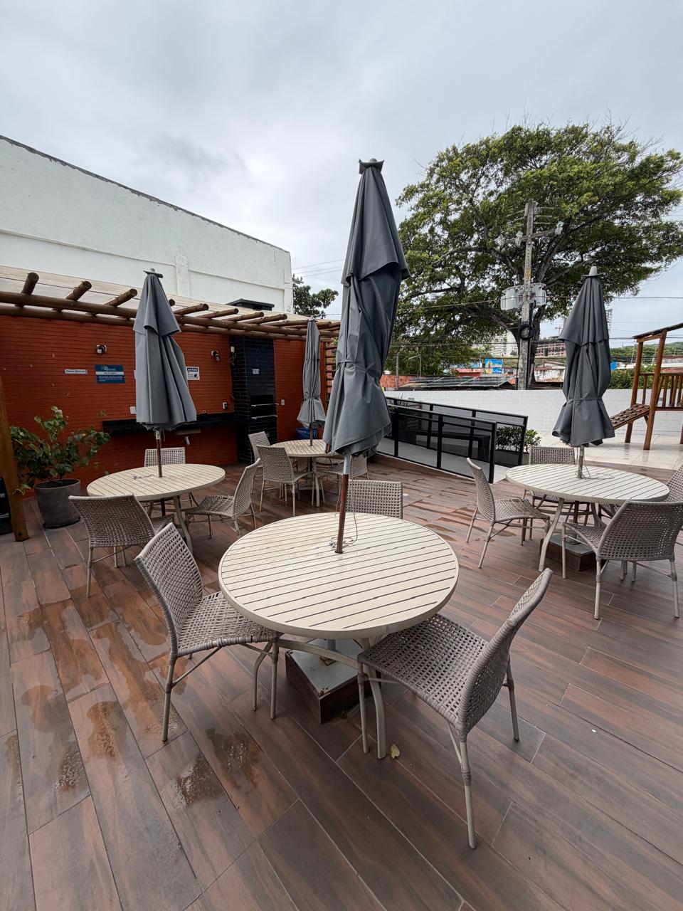 Espaço gourmet com mesas, churrasqueira e área de convivência